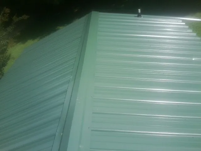 New green metal panels meeting at the ridge of a roof — Flat Roof Repair work by our crew in Murfreesboro