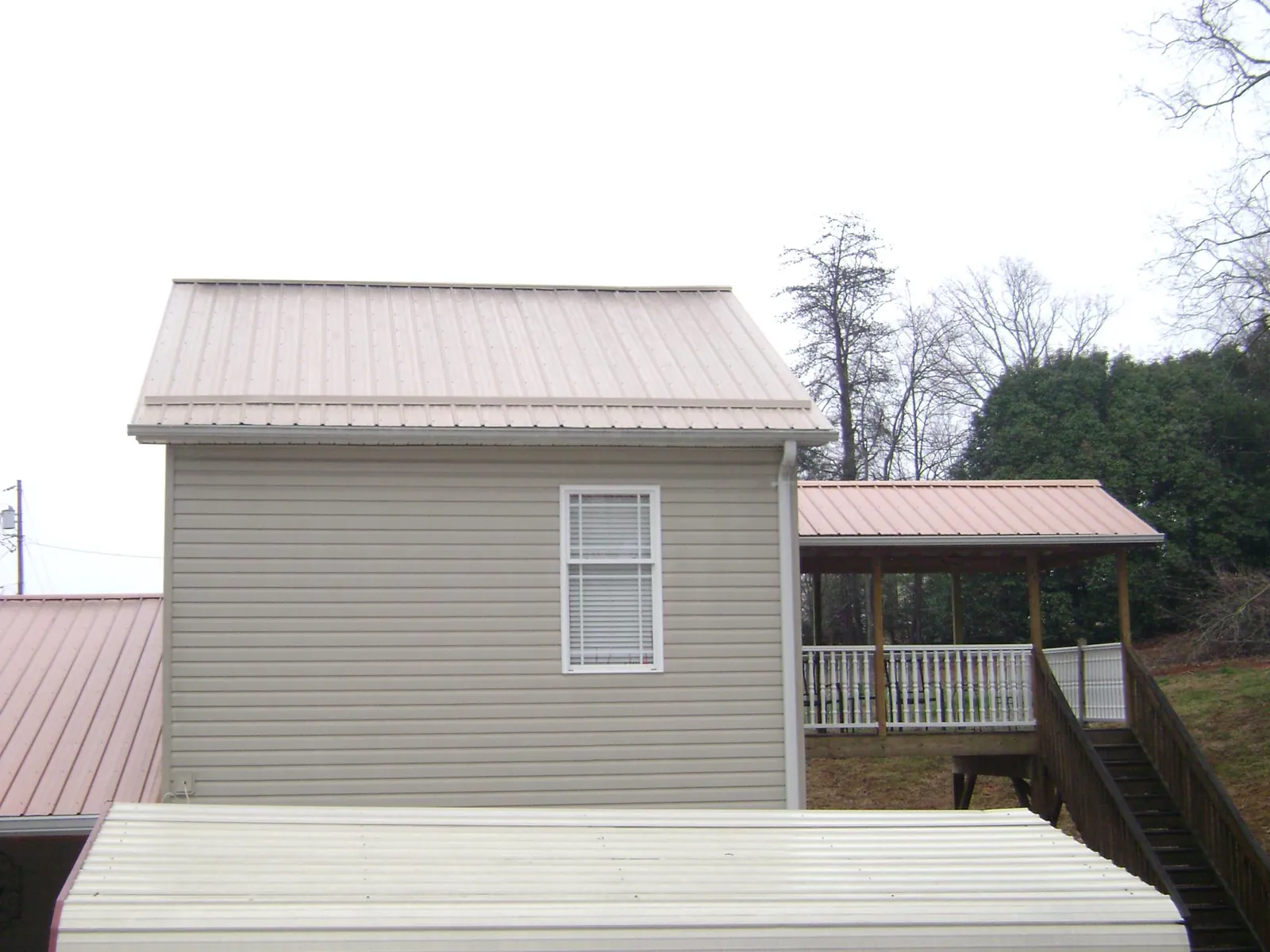 Tan metal roofs on a two story addition and attached porch, from a Roof Replacement job in Murfreesboro