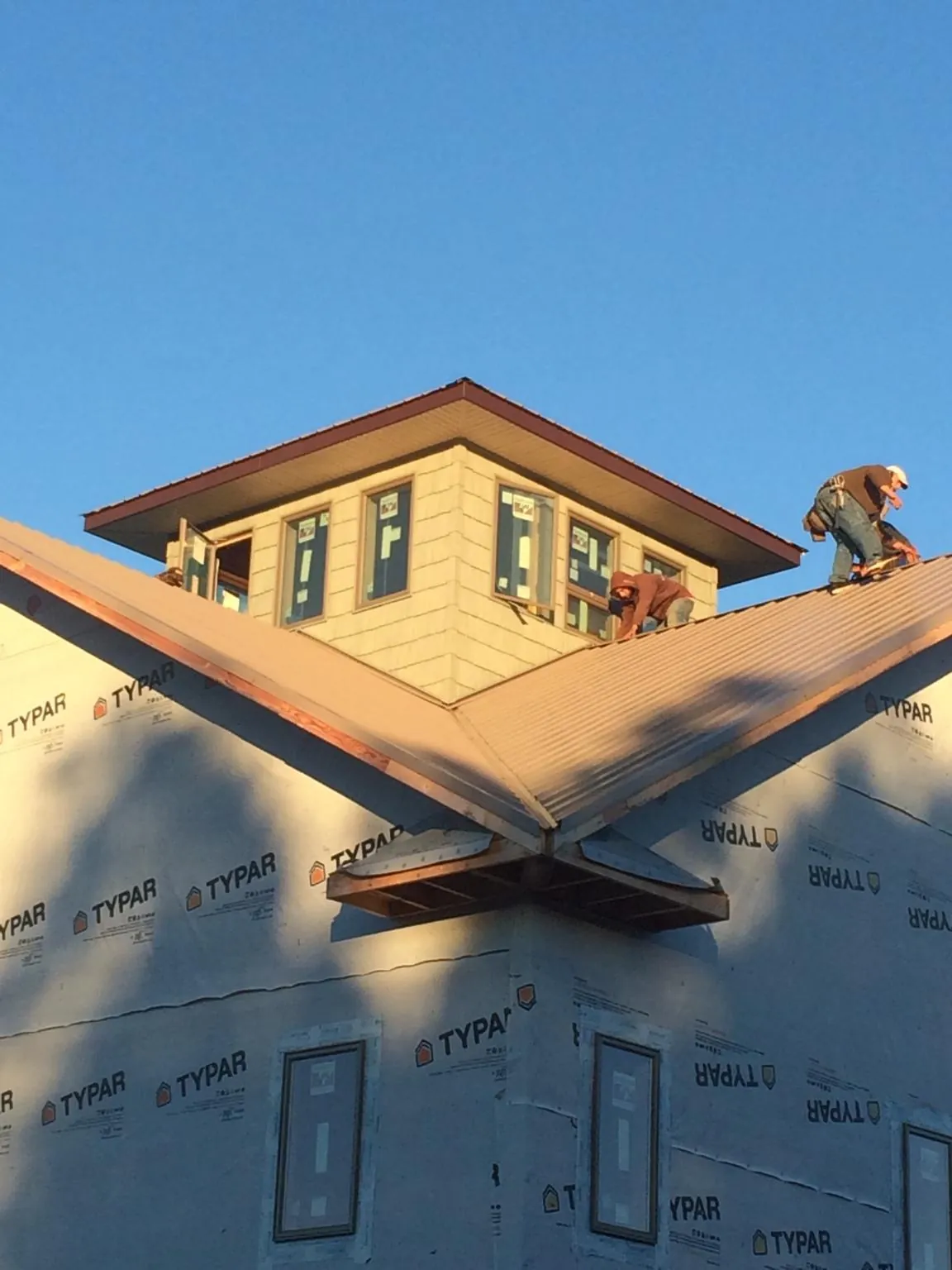 Roofers working around a rooftop cupola on a new metal roof at sunset — Roof Waterproofing in Murfreesboro by Roofing Brothers